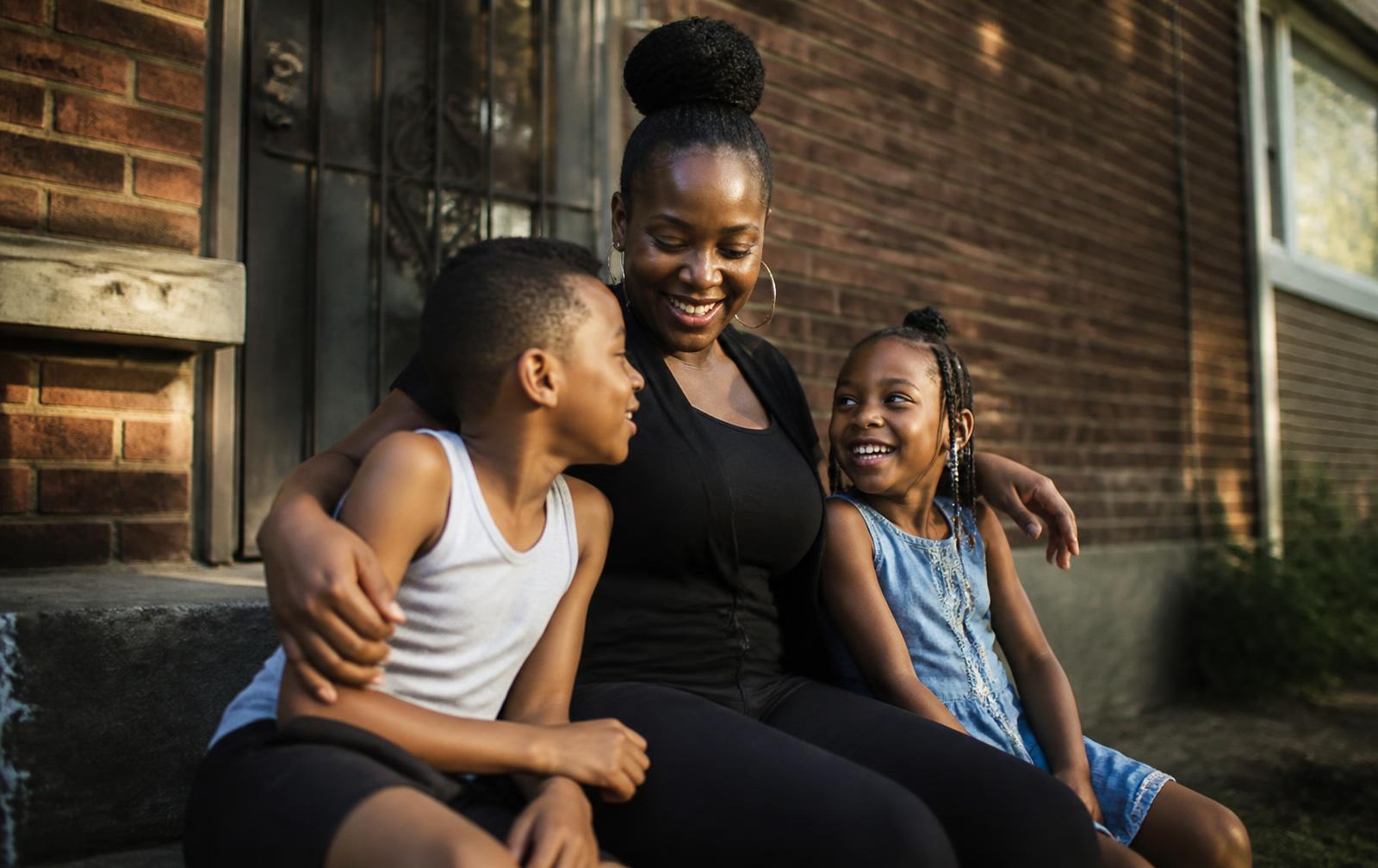 A family sitting together on the front porch of their Tulsa home