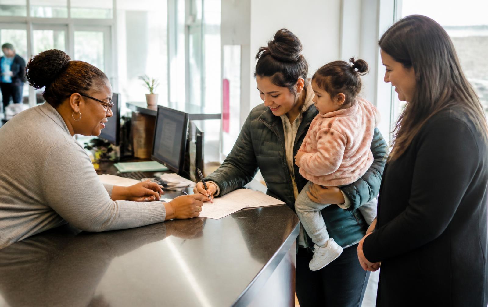 A THA staff member helping a young family at the front desk
