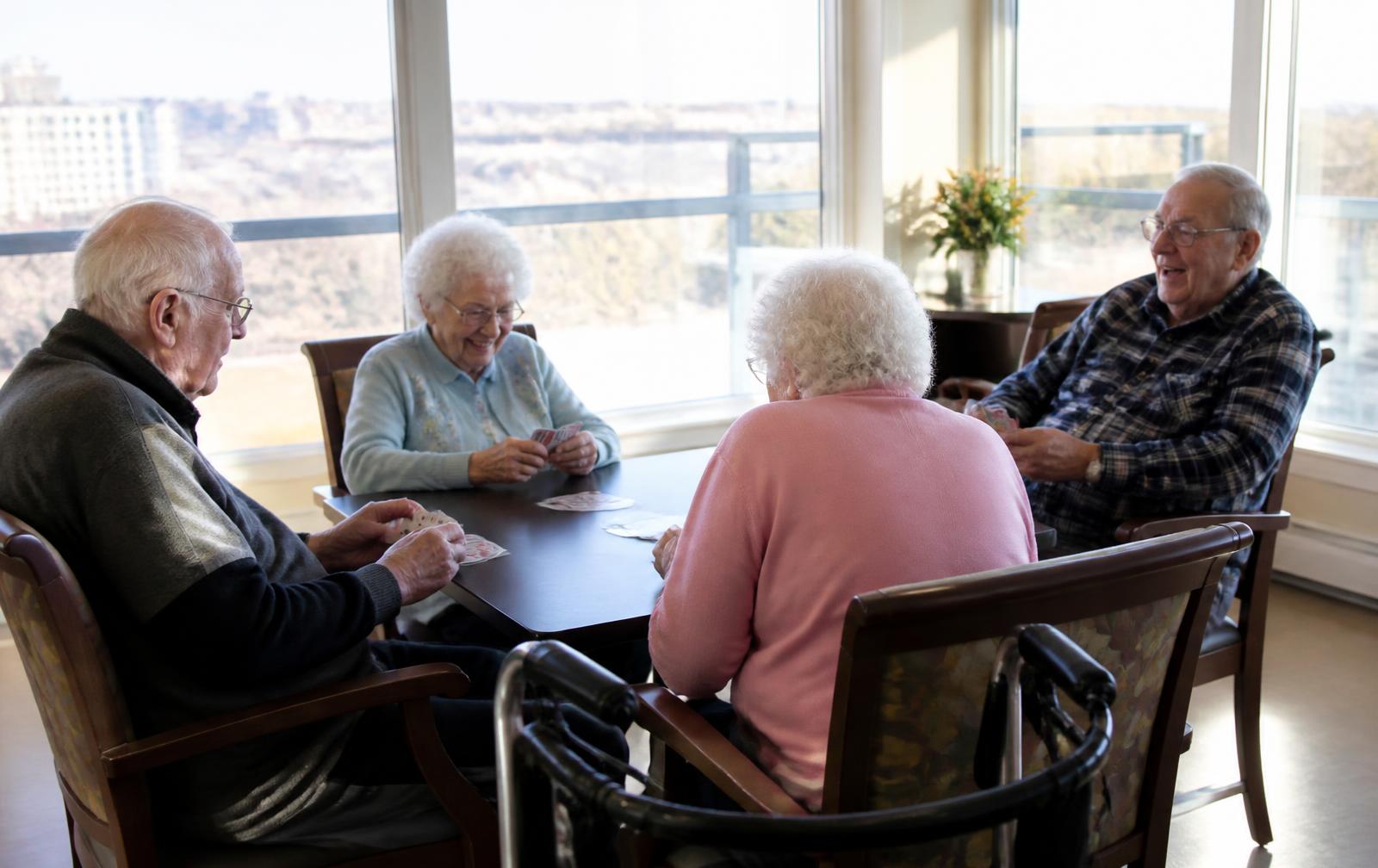 Senior residents playing cards together in a sunlit high-rise community room